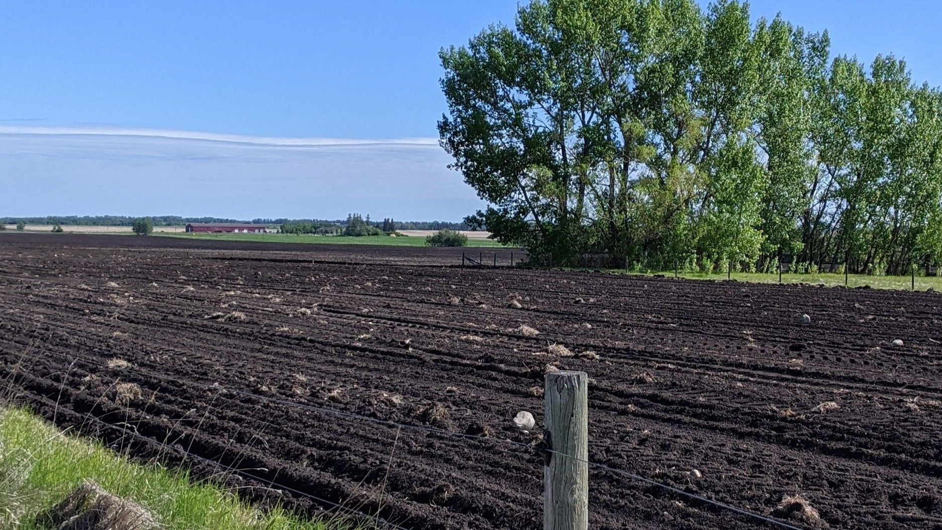 A freshly turned farm field, a bright blue sky, and a barbed wire fence set the scene for the test site for the rock map service.